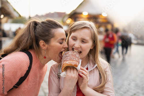 modern mother and child at fair in city eating trdelnik