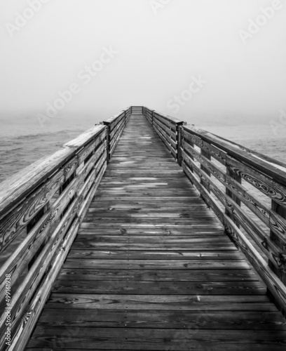 Empty wooden boardwalk pier out into the ocean on a foggy morning