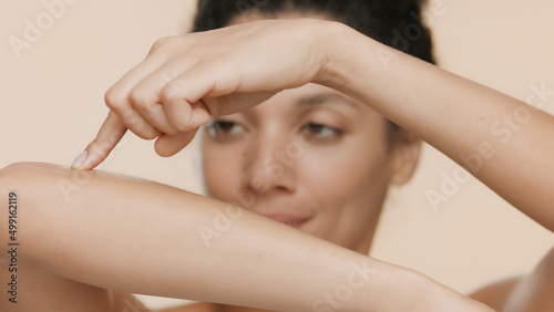 Fotografía Young African American woman strokes her smooth forearm on beige background | Sm