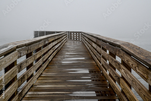 Empty wooden boardwalk pier out into the ocean on a foggy morning