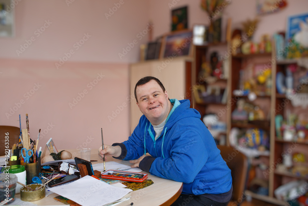 a man with down syndrome is engaged in drawing in a workshop.