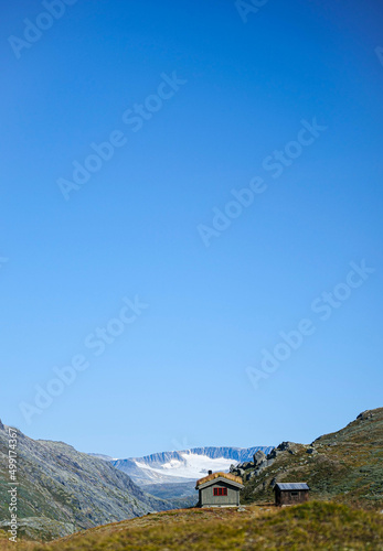 hut house on hill in front of snowy mountains