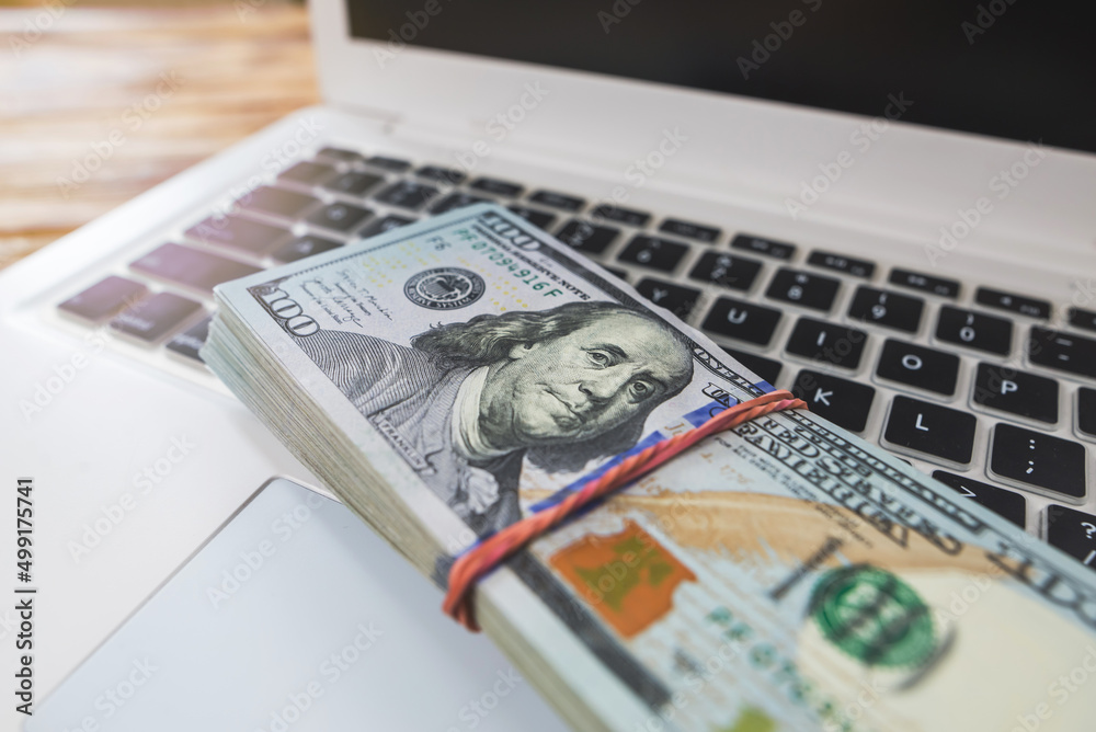  stack of dollars on a laptop keyboard.