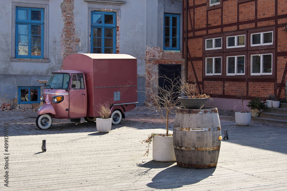 Cargo scooter van. Old wine barrel. Outdoor cafe area.