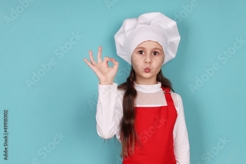 the chef girl shows the OK sign with her hand, isolated on a blue background