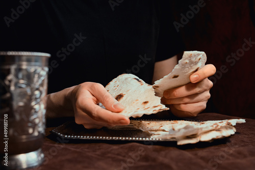 Obraz na plátně Woman's hands breaking unleavened bread for communion for easter with silver dis
