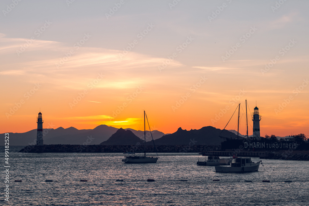 Beautiful view of sunset at Lighthouse in marina with yachts in Turgutreis, Bodrum, Turkey.