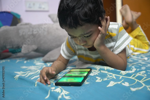 a toddler baby boy engaged in watching and exploring mobile phone.Screen time addiction concept image