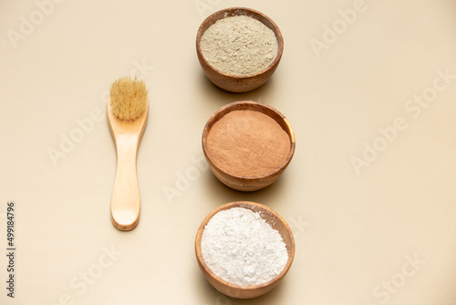 Organic green, red, white face mask clay in wooden bowls with bamboo and goat hair brush on beige background. Home skin care concept.Self care