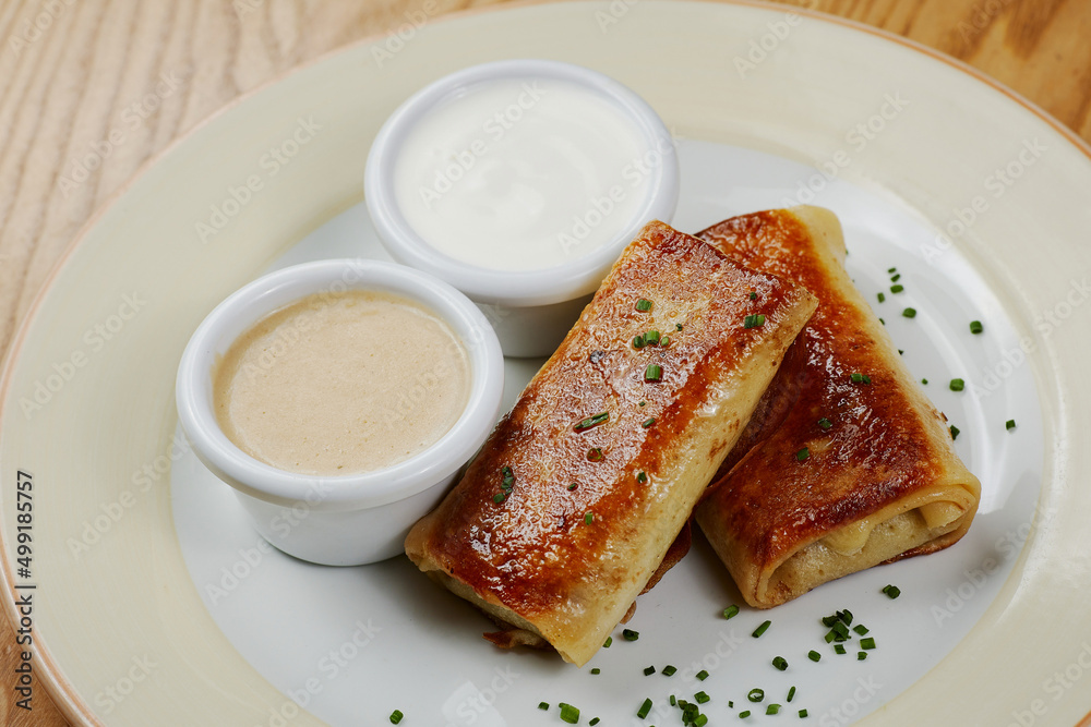 Pancakes with meat, with sauce and sour cream, decorated with herbs Pancakes with meat, with sauce and sour cream, decorated with herbs