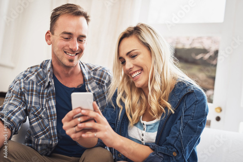 Look at this funny text I just got. Shot of a young couple using a cellphone at home.