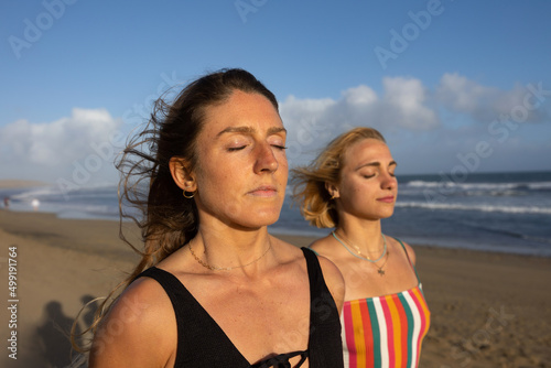 portrait of young women meditating with their eyes closed on the beach © javgutierrez