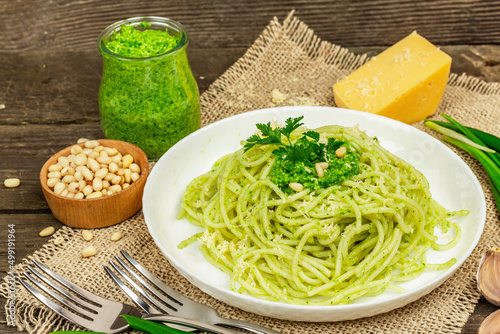 Spaghetti pasta with pesto sauce and fresh ramson leaves. Cutlery, parmesan, pine nuts. Rustic style