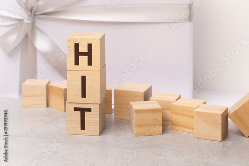 hit - letters on wooden cubes. concept on white gift box background photo