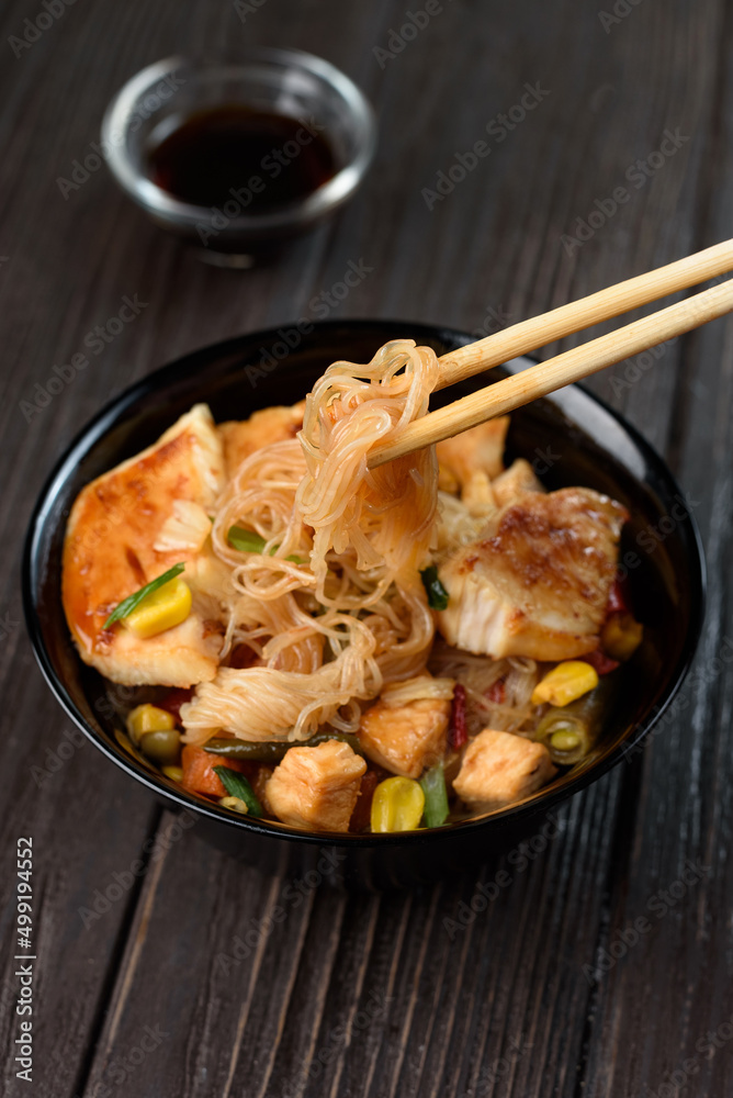 Asian rice noodles funchose with chicken, vegetables and sauce. Near chopsticks and green tea Asian rice noodles funchose with chicken, vegetables and sauce. Near chopsticks and green tea