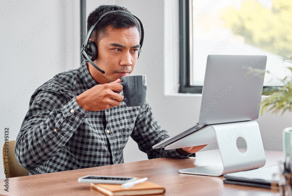 A sip of coffee is always the solution. Cropped shot of a handsome young male call center agent drinking coffee while working on his laptop. A sip of coffee is always the solution. Cropped shot of a handsome young male call center agent drinking coffee while working on his laptop.