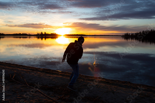 silhouette of a person skipping stones in the sunset