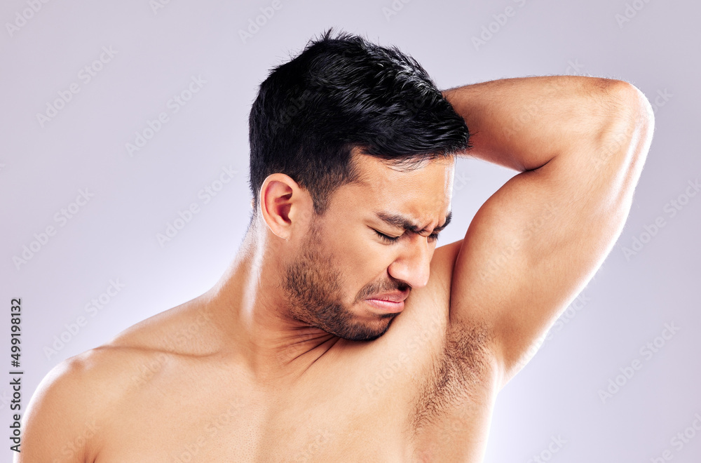 Im going to need something a little stronger. Studio shot of a man frowning while smelling his armpit.
