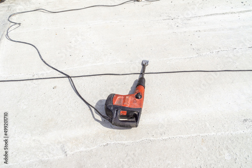 impact drill with a nozzle flat chisel lies on the concrete surface of the ceiling