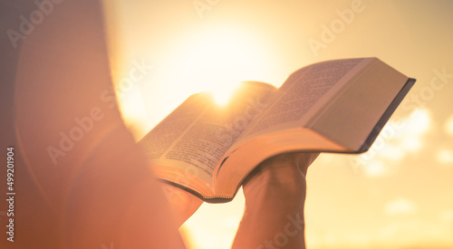 Person holding reading bible up to the sunlight photo