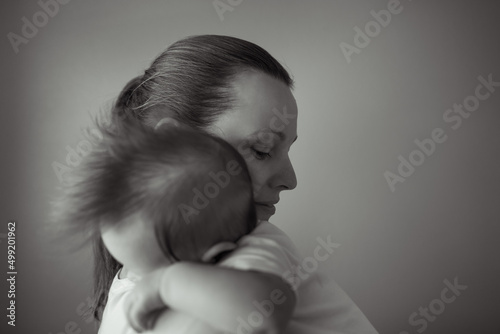 Isolated portrait of mother holding child sleeping in her arms. 