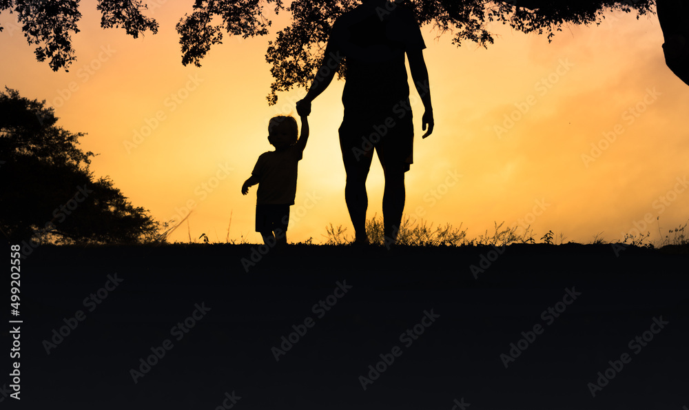 Little child holding fathers hand walking at sunset. Children support trust and care concept Little child holding fathers hand walking at sunset. Children support trust and care concept