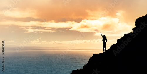 Achievement, goal setting and overcoming life obstacles concept. Victory on a mountain top. Woman with fist up to the sky. 
