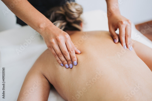 Unrecognizable therapist making back and scapula massage to a female patient with back pain. Relaxing and de-stress