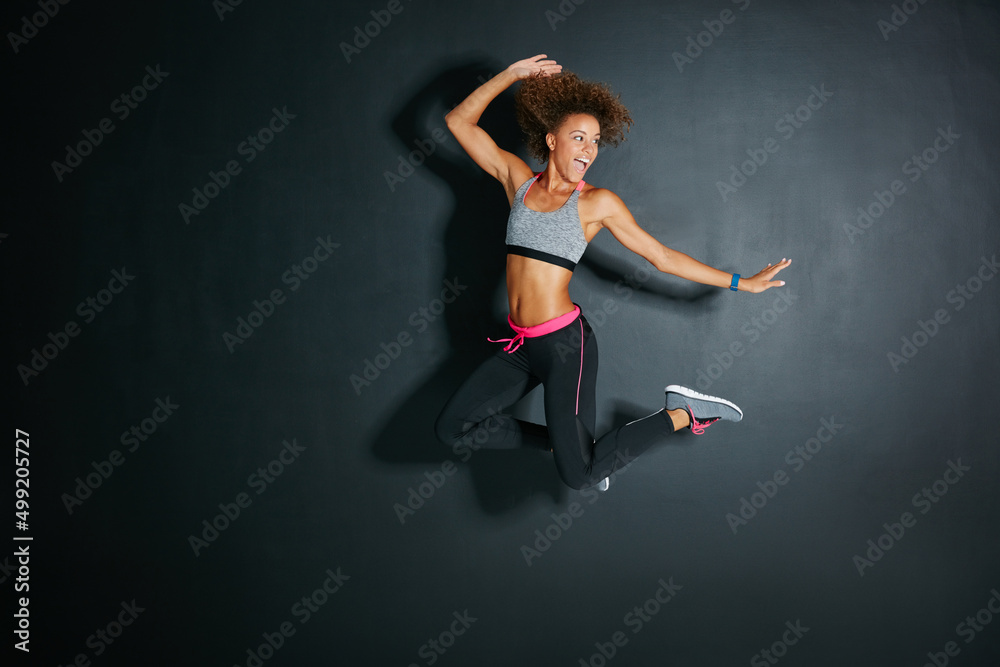 Always look on the bright side of life. Shot of a sporty young woman jumping against a grey background.