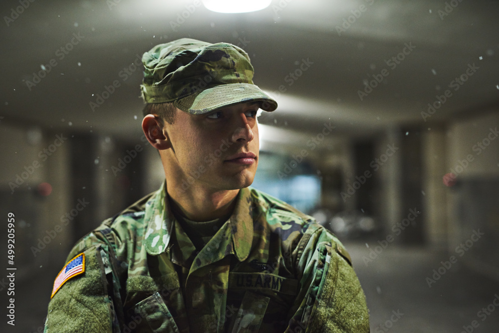 Stay alert, stay alive. Shot of a young soldier standing outside on a cold night at a military academy.