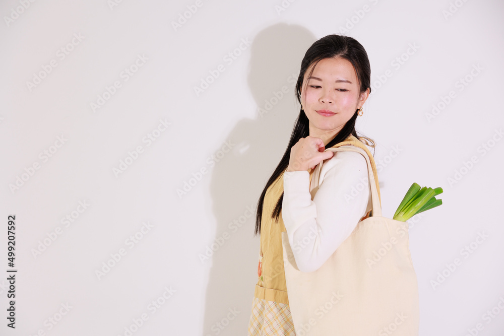 買い物袋を持つエプロンを着た日本人女性 買い物袋を持つエプロンを着た日本人女性