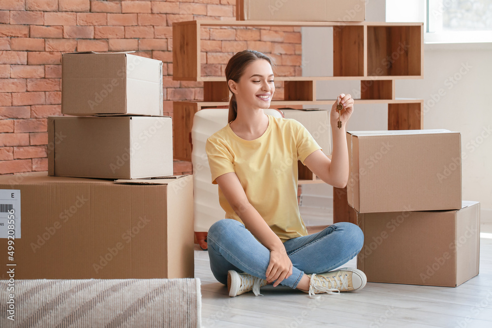 Happy young woman with key sitting on floor in her new apartment Happy young woman with key sitting on floor in her new apartment