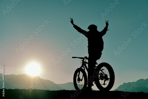 person saying goodbye to the sun on peak mountains with bicycle