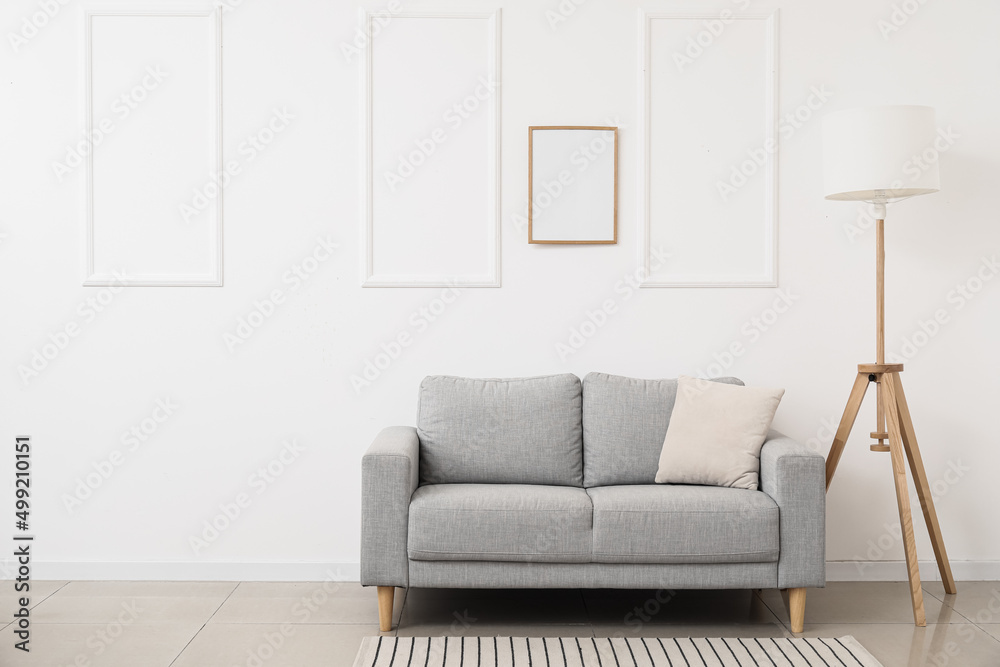 Fototapeta premium New sofa and modern lamp near white wall