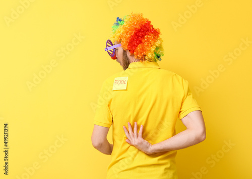 Tablou canvas Funny man in disguise and with sticky note on his back against yellow background