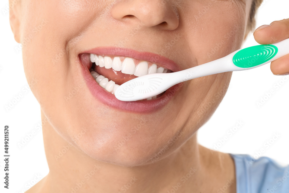 Fototapeta premium Beautiful mature woman brushing teeth on white background, closeup