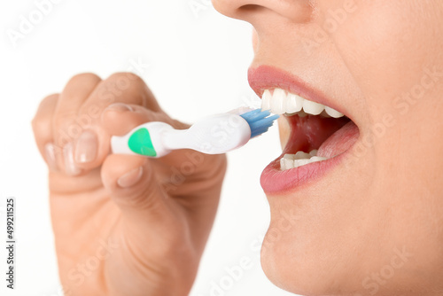 Beautiful mature woman brushing teeth on white background, closeup