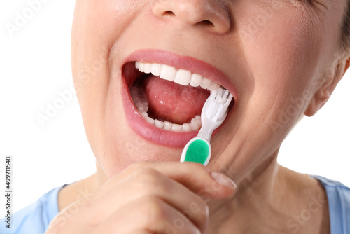 Beautiful mature woman brushing teeth on white background  closeup