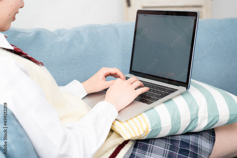 Fototapeta premium ソファーでラップトップを操作している女子高生