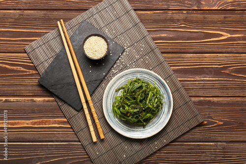 Plate with healthy seaweed salad and sesame on wooden background