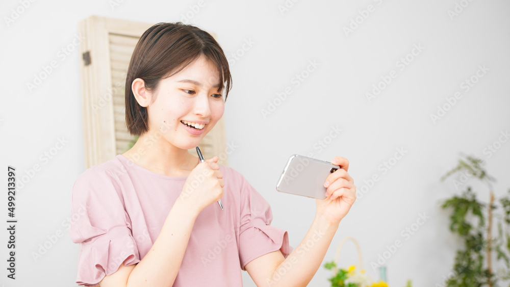 スマートフォンを観ながら勉強をする女性 スマートフォンを観ながら勉強をする女性