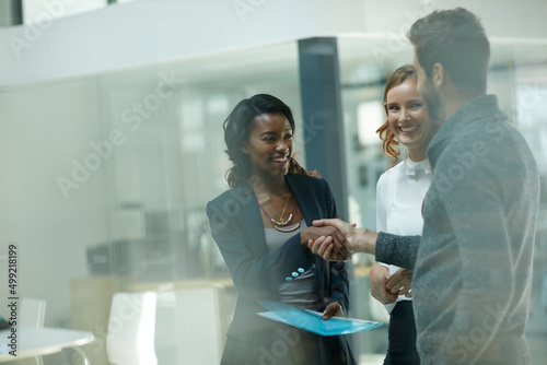 Welcoming a new member to the team. Cropped shot of businesspeople shaking hands in an office.