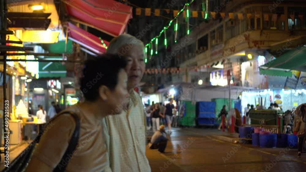 Two Asian elderly couple looking for street food restaurant night life explore in Hong Kong Two Asian elderly couple looking for street food restaurant night life explore in Hong Kong