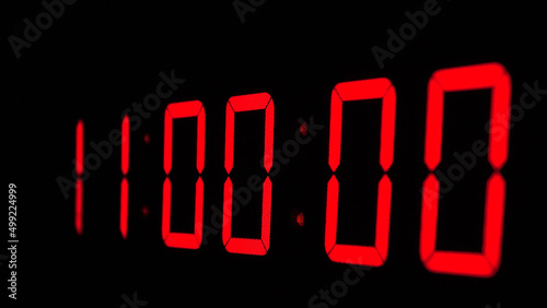 Digital timer on a black background. Light panel with red numbers
