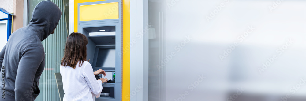 Thief Looking At Woman Entering The Pin In ATM Thief Looking At Woman Entering The Pin In ATM