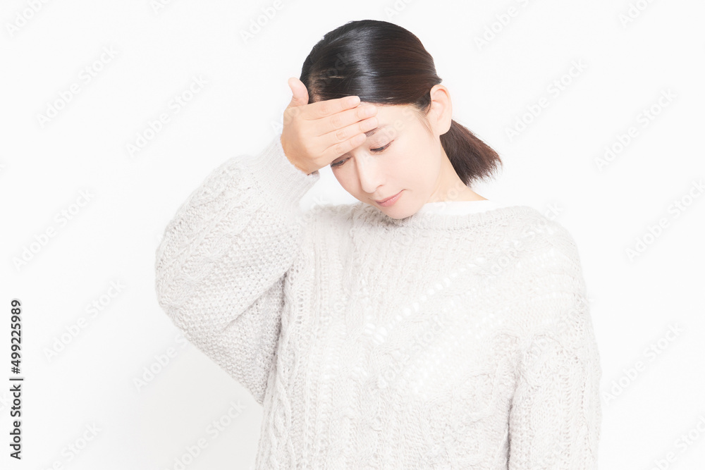 体調不良で頭に手を当てる女性