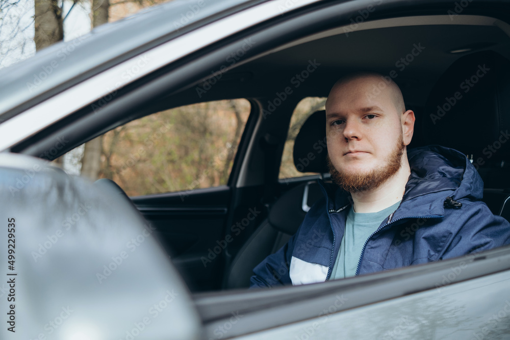 Handsome elegant bearded bald serious man drives a car