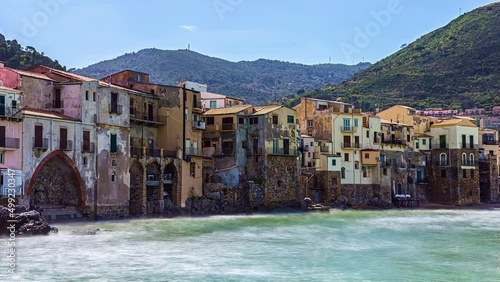 View of residentail bbuildings in Puritate Beach in Salento, Apulia, Italy with waves crashing on the beach in timelapse. Beautiful hilly terrain covered by dense green vegetation in the background. photo