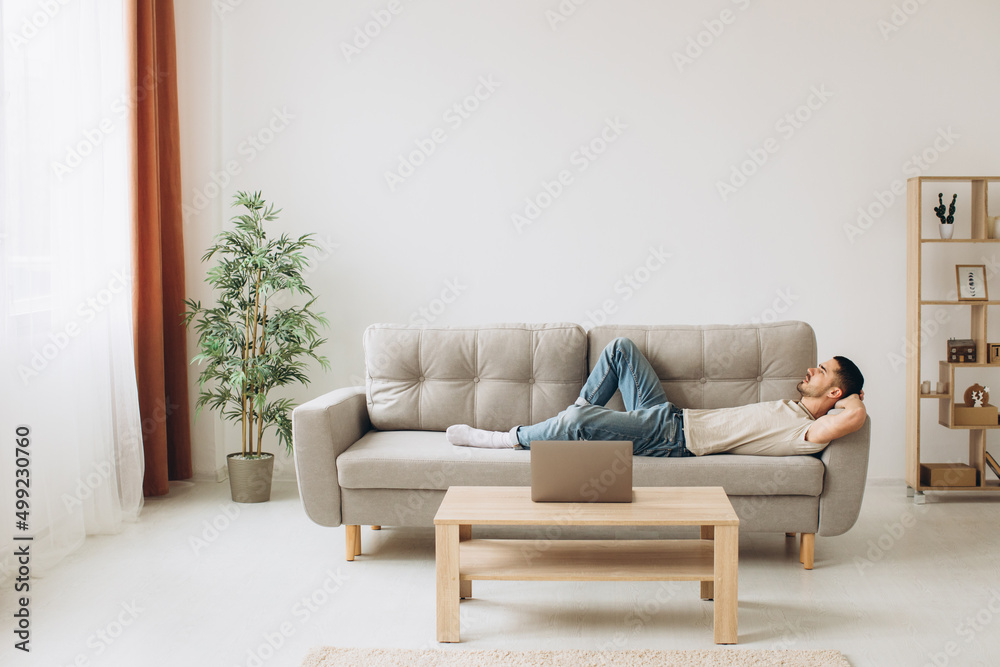 Young Man Relaxing On Sofa In Living Room Young Man Relaxing On Sofa In Living Room