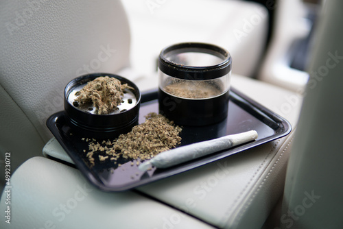 car background close up marijuana bud flowers of cannabis. grinder and shredded cannabis joint and a packet photo